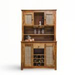 Rustic solid wood bar cabinet with rattan cane doors, wine bottle cubbies, hanging glass rack, and open shelves for home bar storage.